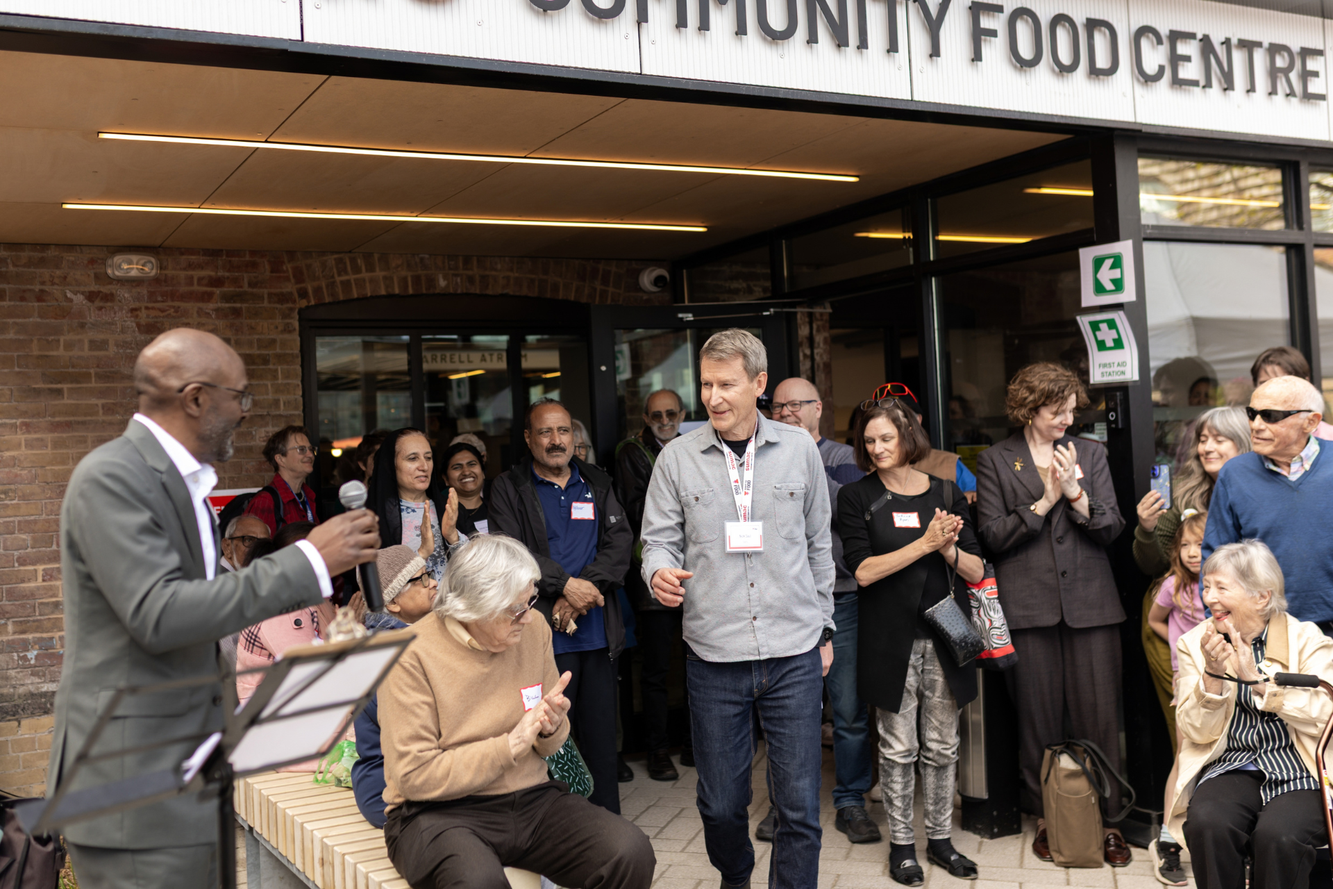 Nick Saul sourit, entouré de personnes qui applaudissent, lors de l'inauguration du centre alimentaire communautaire Sumac.